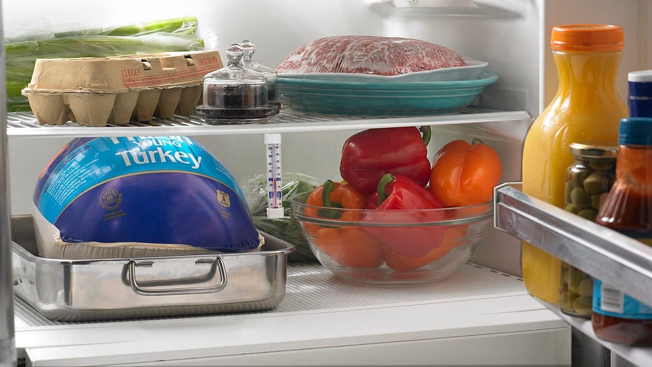 Un frigorifero aperto e pieno di cibo, con verdure, uova, carne e bevande sui ripiani
