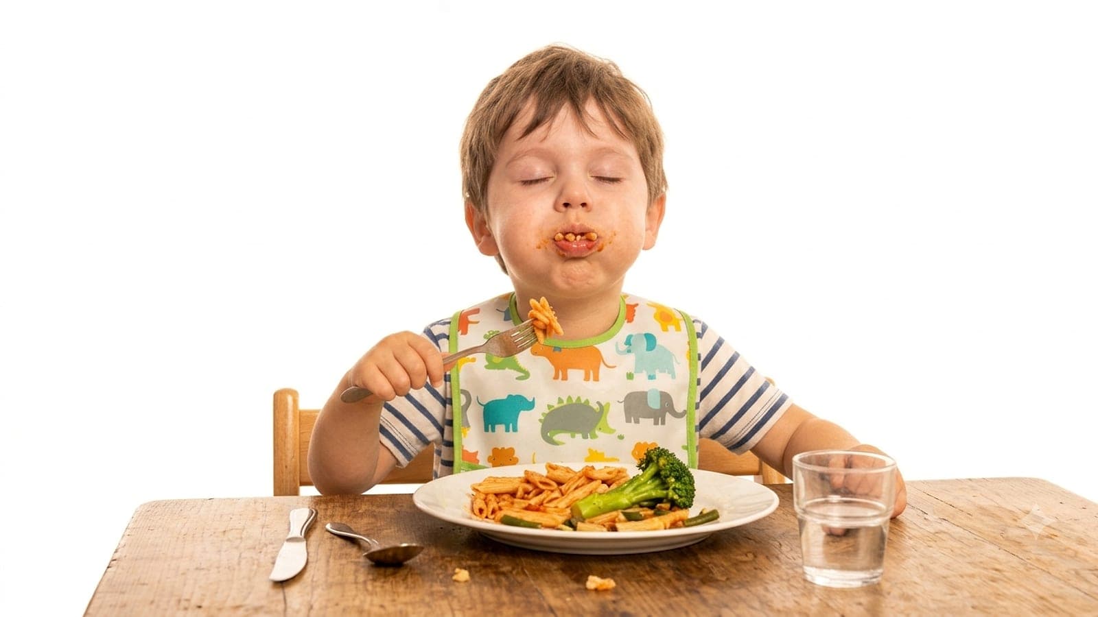 Lo stesso bambino della foto di apertura, questa volta mangia pasta e broccoli a occhi chiusi